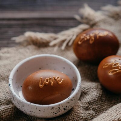 Brown Easter eggs with handwritten words on burlap for a rustic celebration.